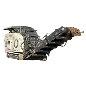 A large, industrial impact crusher is seen conveying crushed material on a moving belt.